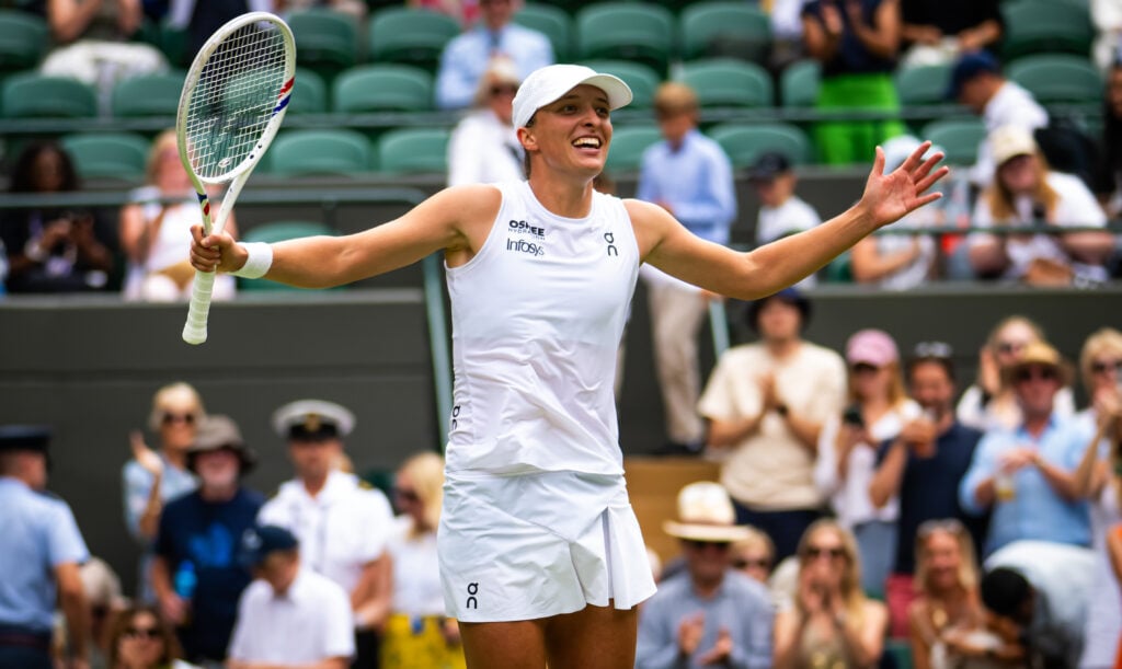 Iga Swiatek lifts her arms out wide in celebration