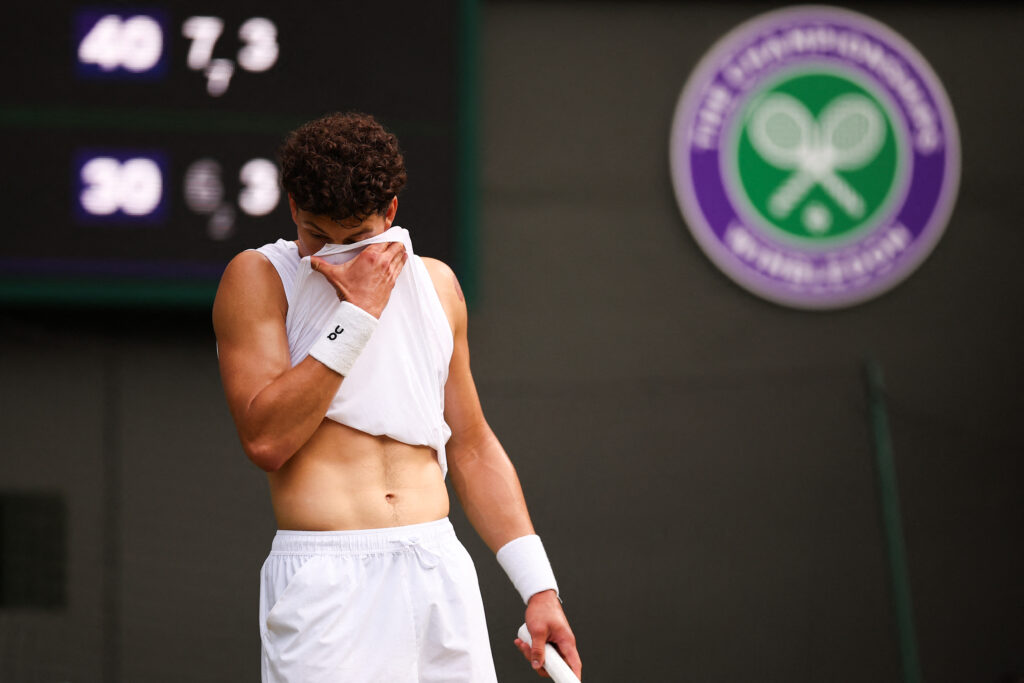 Ben Shelton covers his face with his top