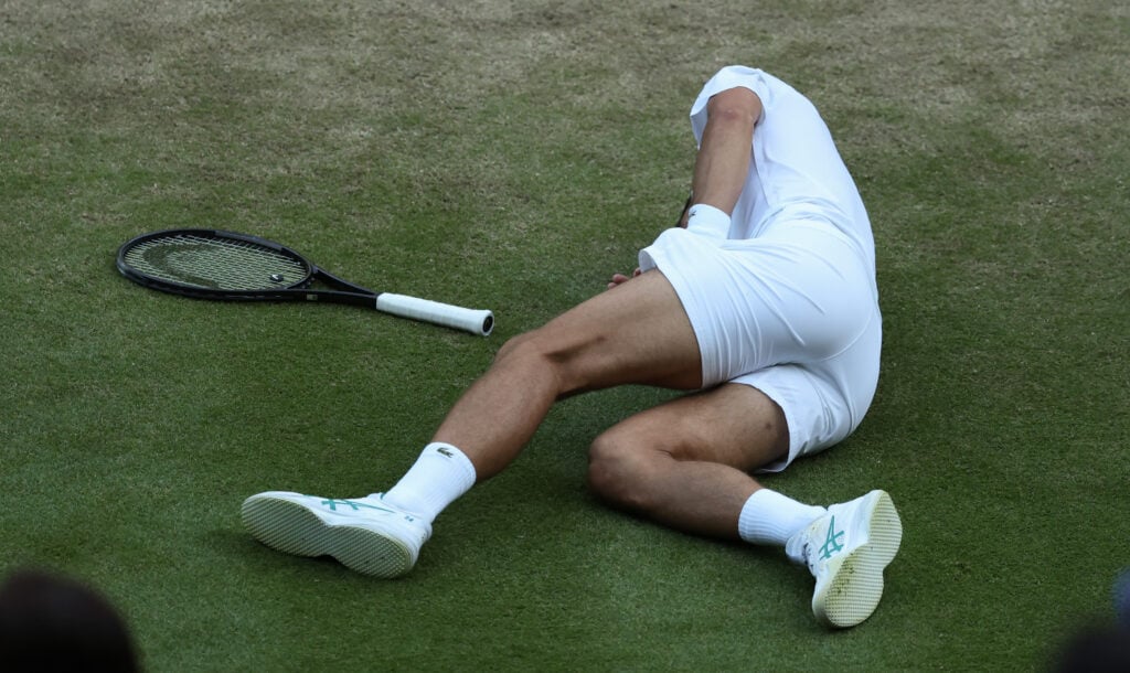 Novak Djokovic lies on his side on the court after falling