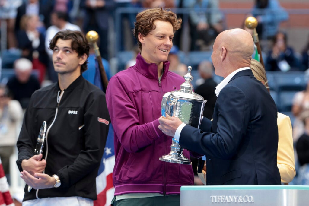 Winner Jannik Sinner of Italy receives the trophy from Andre Agassi, left finalist Taylor Fritz of USA during the trophy ceremony following the Men's Final on Day Fourteen of the 2024 US Open at USTA Billie Jean King National Tennis Center on September 8, 2024 in the Flushing neighborhood of the Queens borough of New York City.