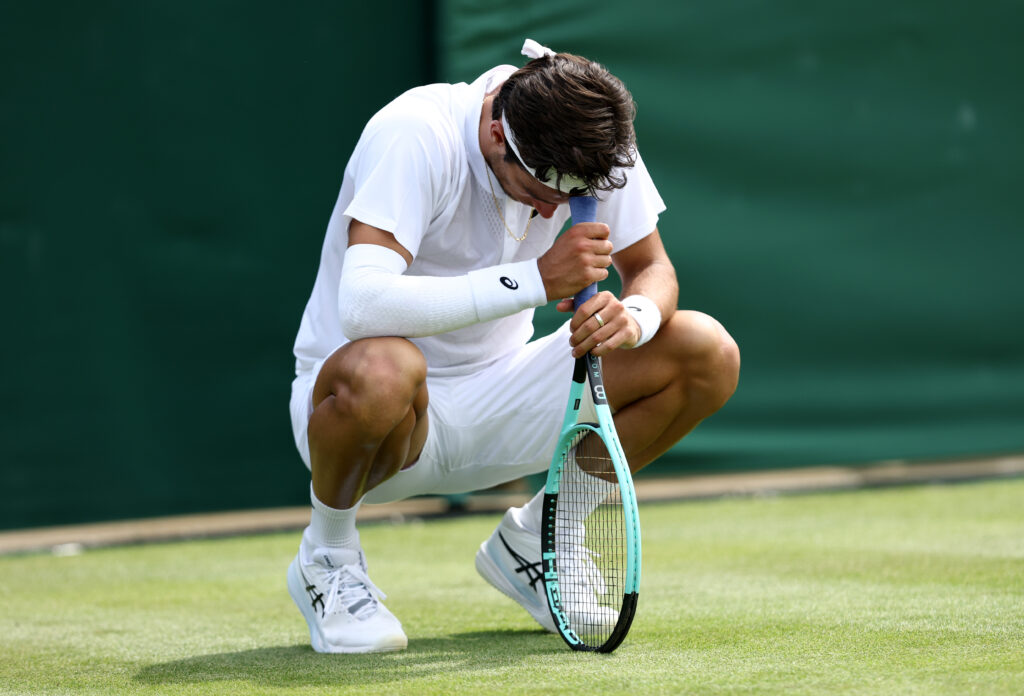 Lorenzo Musetti looks dejected, resting his head on his racket