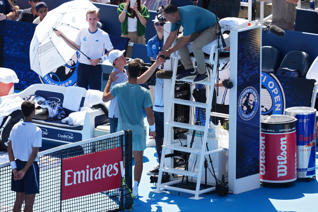 Jannik Sinner of Italy meets with Carlos Alcaraz of Spain and umpire Mohamed Lahyani to retire from the men's singles finals during Day 12 of the Cincinnati Open at the Lindner Family Tennis Center on August 18, 2025 in Mason, Ohio.