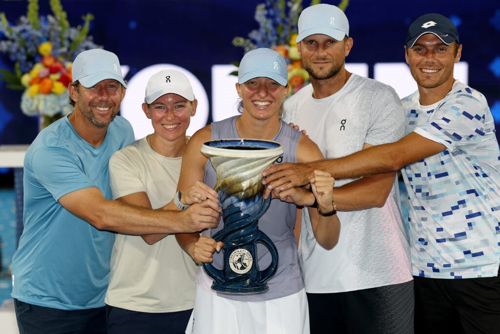 Iga Swiatek of Poland poses with the Rookwood Cup alongside coach Wim Fissette, sports psychologist Daria Abramowicz, fitness coach Maciej Ryszczuk and hitting partner Kacper Zuk after defeating Jasmine Paolini of Italy during the women's final of the Cincinnati Open at Lindner Family Tennis Center on August 18, 2025 in Mason, Ohio.