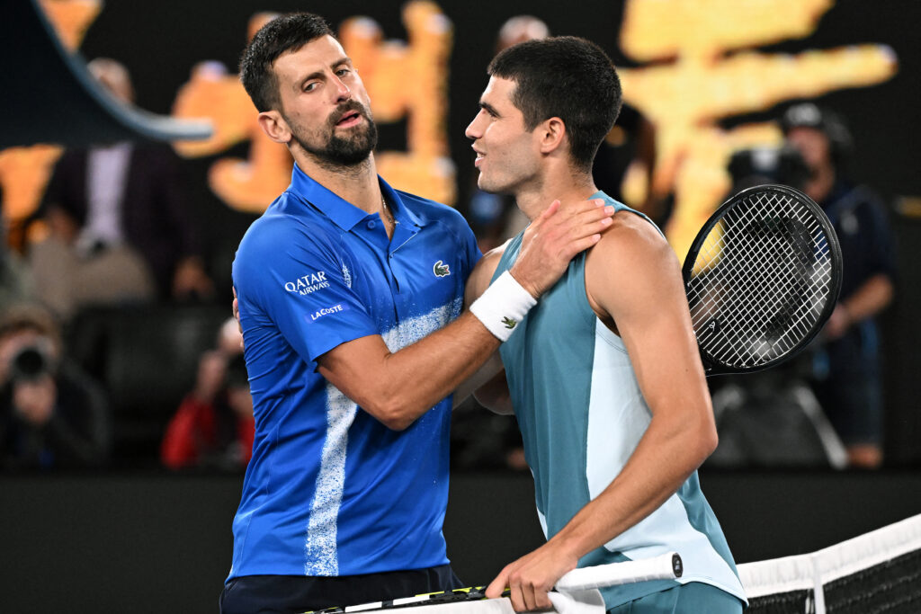 Serbia's Novak Djokovic (L) embraces Spain's Carlos Alcaraz after their men's singles quarterfinal match on day ten of the Australian Open tennis tournament in Melbourne on January 22, 2025.