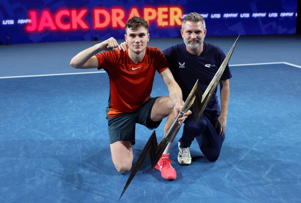 Jack 'The Power' Draper of Great Britain and coach James Trotman with the trophy after winning the Final match against Holger 'The Viking' Rune of Denmark during Day Three of the UTS Grand Final London at ExCel London on December 17, 2023 in London, England.