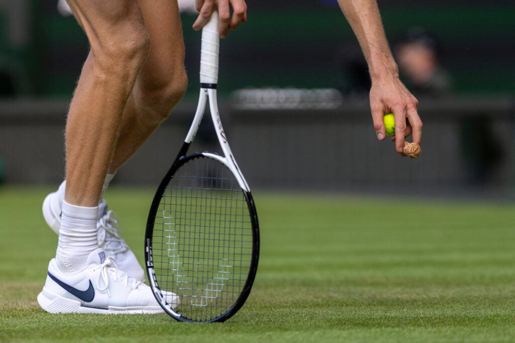 Jannik Sinner of Italy picks up a champagne cork which landed on the grass court during his match against Carlos Alcaraz of Spain in the Gentlemen's Singles Final on Centre Court during the Wimbledon Lawn Tennis Championships at the All England Lawn Tennis and Croquet Club at Wimbledon on July 13th, 2025, in London, England.