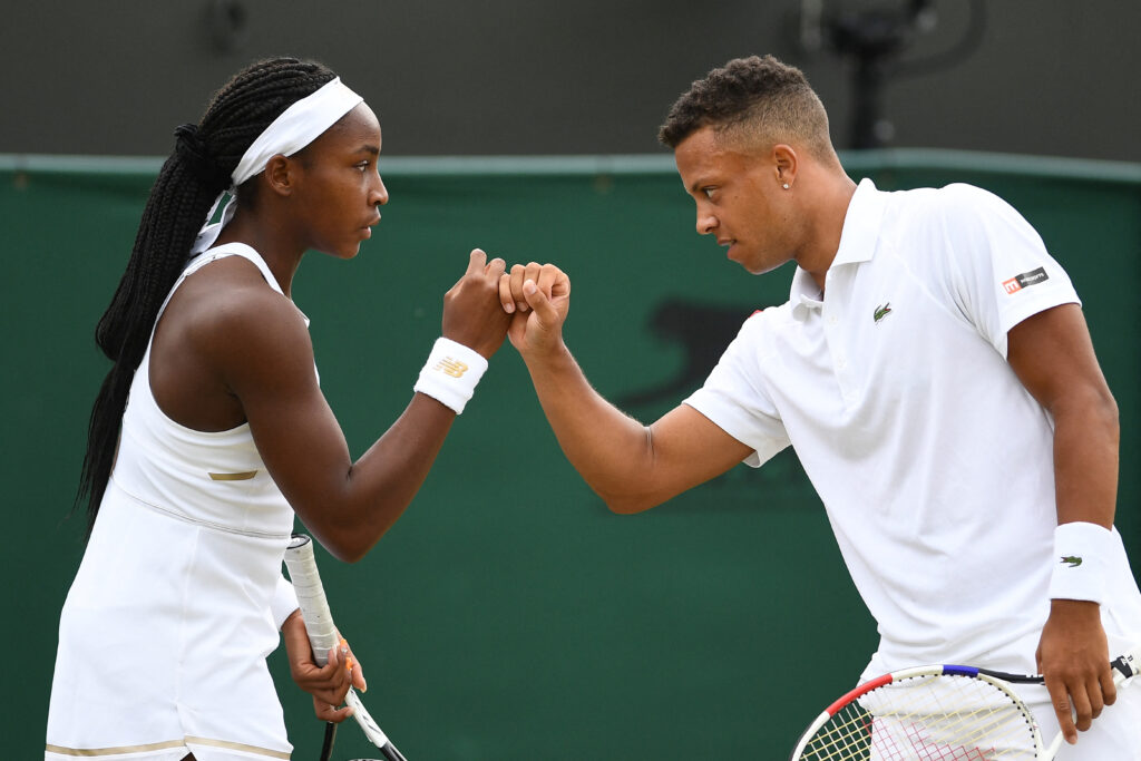 Britain's Jay Clarke (R) and US player Cori Gauff (L) touch hands between points against Sweden's Robert Lindstedt and Latvia's Jelena Ostapenko during their mixed doubles first round match on the sixth day of the 2019 Wimbledon Championships at The All England Lawn Tennis Club in Wimbledon, southwest London, on July 6, 2019.
