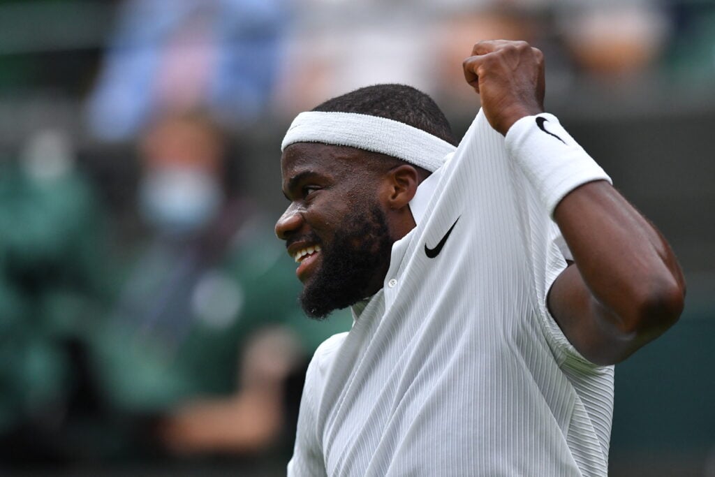 US player Frances Tiafoe smiles after winning an appeal during play against Greece's Stefanos Tsitsipas during their men's singles first round match on the first day of the 2021 Wimbledon Championships at The All England Tennis Club in Wimbledon, southwest London, on June 28, 2021.