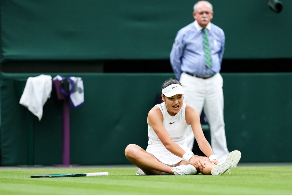 Emma Raducanu grimaces and holds her ankle
