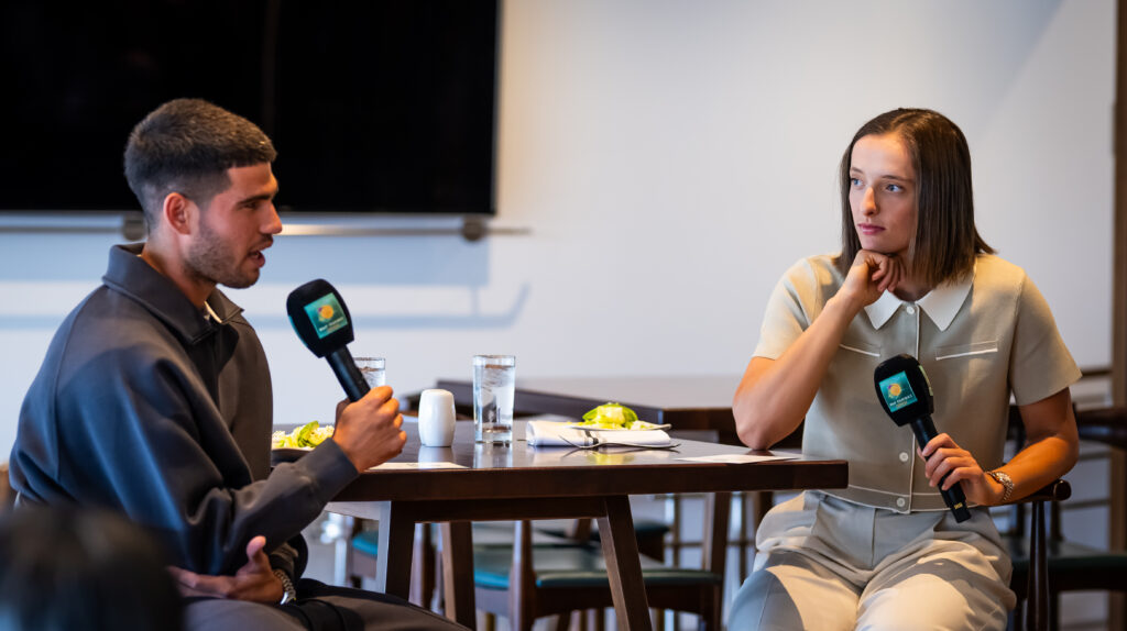 Iga Swiatek and Carlos Alcaraz chat, sat down at a table
