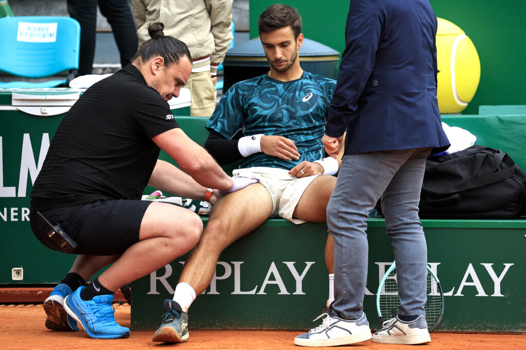 Italy's Lorenzo Musetti (C) receives medical treatment between games as he plays against Spain's Carlos Alcaraz during the Monte Carlo ATP Masters Series Tournament final tennis match at the Monte Carlo Country Club in Roquebrune-Cap-Martin on April 13, 2025.