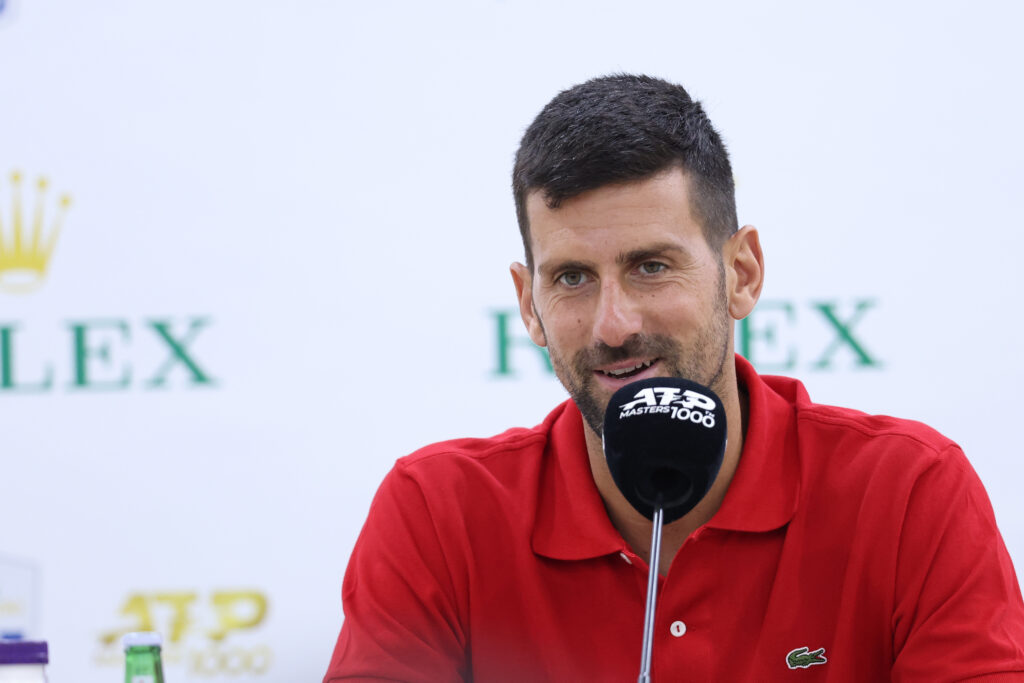 Novak Djokovic speaks into a microphone at a press conference