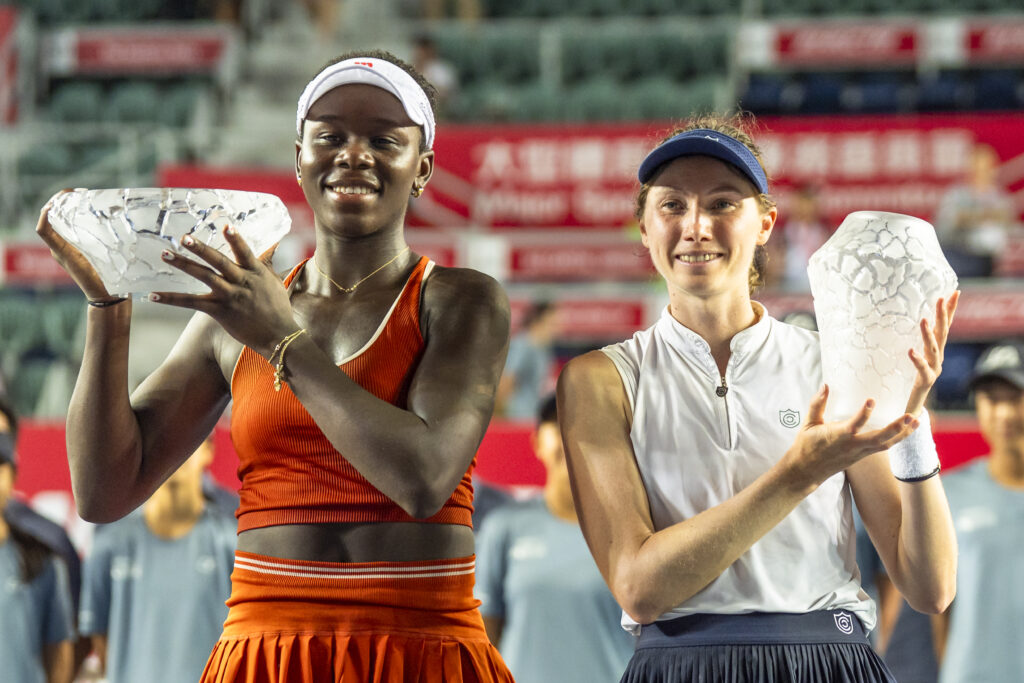 Victoria Mboko of Canada (L) and Cristina Buca of Spain (R) pose for photo with trophy during the award presentation in the women's singles final match on day seven of the Prudential Hong Kong Tennis Open at Victoria Park on November 2, 2025 in Hong Kong, China.