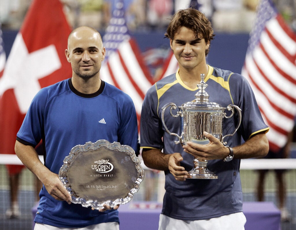 Roger Federer of Switzerland (R) and Andre Agassi of the US pose with their trophies during the victory ceremony after the US Open final.