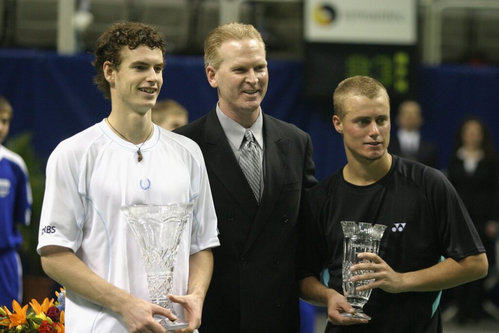 Andy Murray of Great Britain smiles alongside an SAP Official and Lleyton Hewitt, of Austalia, after winning his match against Hewitt in the SAP Open at the HP Pavilion on February 19, 2006 in San Jose, California. Murray, 18, is the youngest person to win the SAP Open since Michael Chang, at 16 years, in 1988.