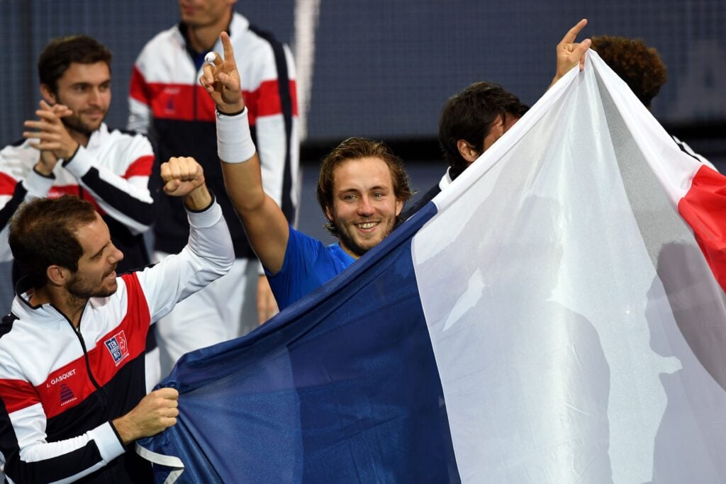 France's Lucas Pouille celebrates with the French flag as celebrates after winning his singles rubber 5 match against Belgium's Steve Darcis at the Davis Cup World Group final tennis match between France and Belgium