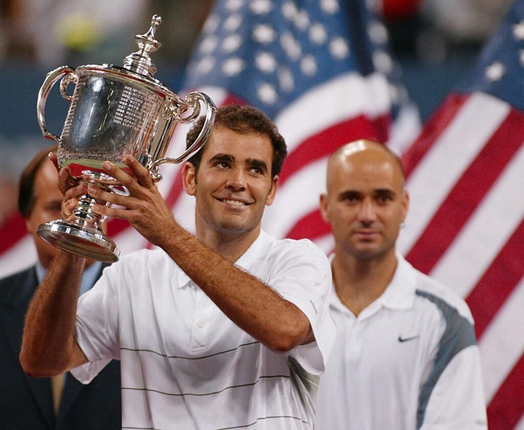 Pete Sampras of the US holds up the trophy as Andre Agassi of the US looks on after their men's singles final match at the US Open Tennis Tournament 08 September, 2002 at Flushing Meadows, NY. Sampras won his 14th grand slam title over Agassi 6-3, 6-4, 5-7, 6-4.