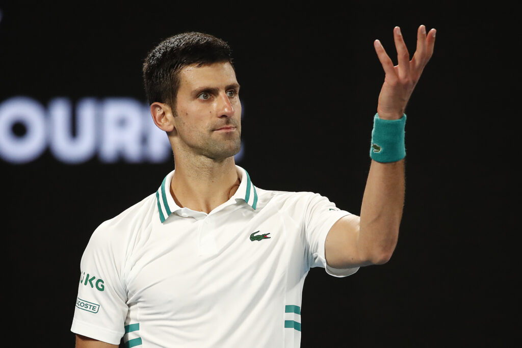 Novak Djokovic holds up his arm in confusion