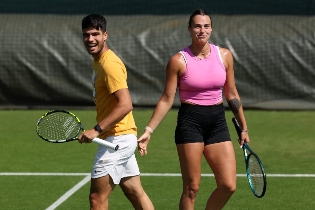 Carlos Alcaraz of Spain interacts with Aryna Sabalenka during practice prior to The Championships Wimbledon 2024 at All England Lawn Tennis and Croquet Club on June 26, 2024 in London, England.