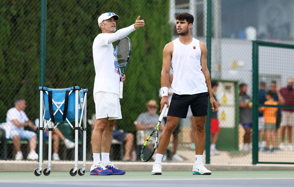 Carlos Alcaraz of Spain listens to his coach Samuel Lopez as he trains in preparation for the Cincinnati Open and US Open at Real Sociedad Club de Campo Murcia