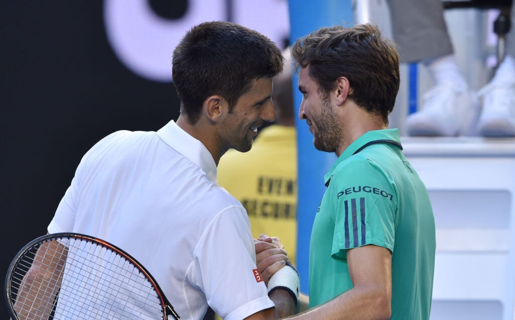 Serbia's Novak Djokovic (l) shakes hands as he celebrates after victory induring his men's singles match against France's Gilles Simon on day seven of the 2016 Australian Open tennis tournament in Melbourne on January 24, 2016.