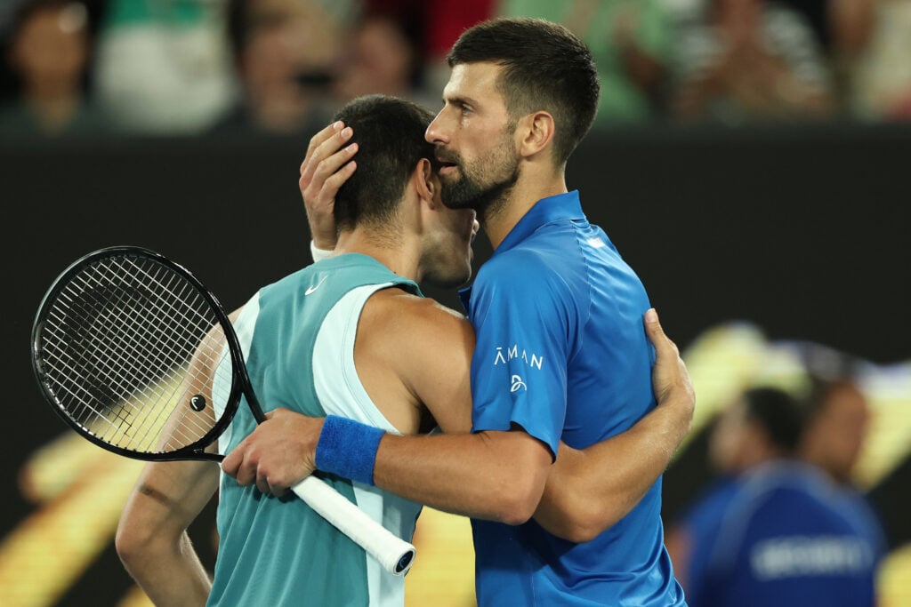 Novak Djokovic of Serbia (R) embraces Carlos Alcaraz of Spain following victory in the Men's Singles Quarterfinal match during day 10 of the 2025 Australian Open at Melbourne Park on January 21, 2025 in Melbourne, Australia.