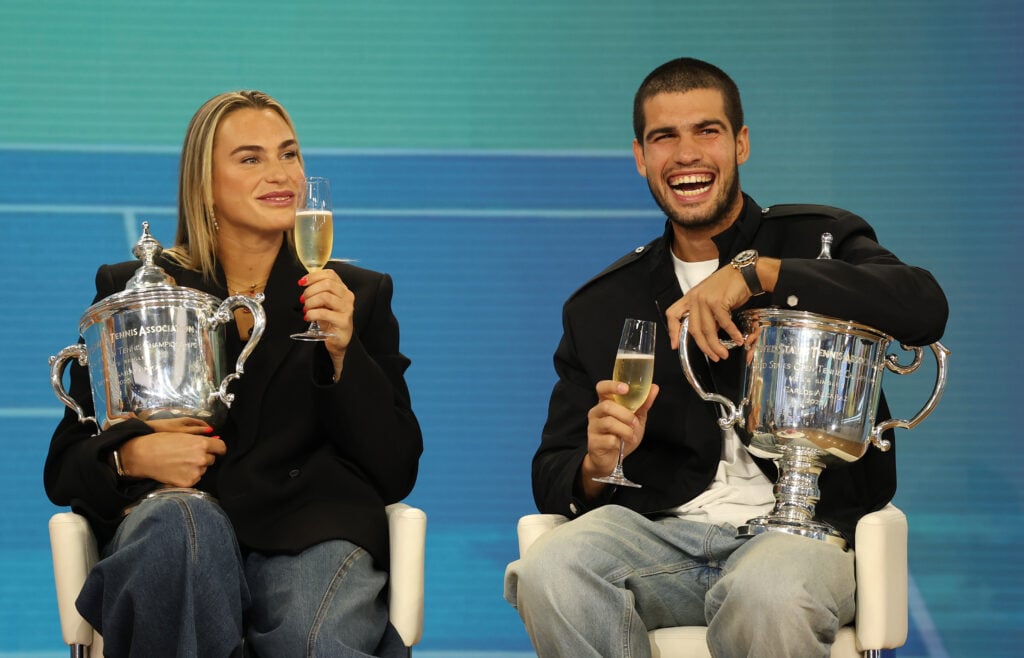 US Open 2025 Champions Aryna Sabalenka and Carlos Alcaraz of Spain hold a glass of champagne as they are interviewed holding their trophies while filming for the Today Show following following their victories in the Men's and Women's Singles finals at Rockefeller Plaza on September 08, 2025 in New York City.