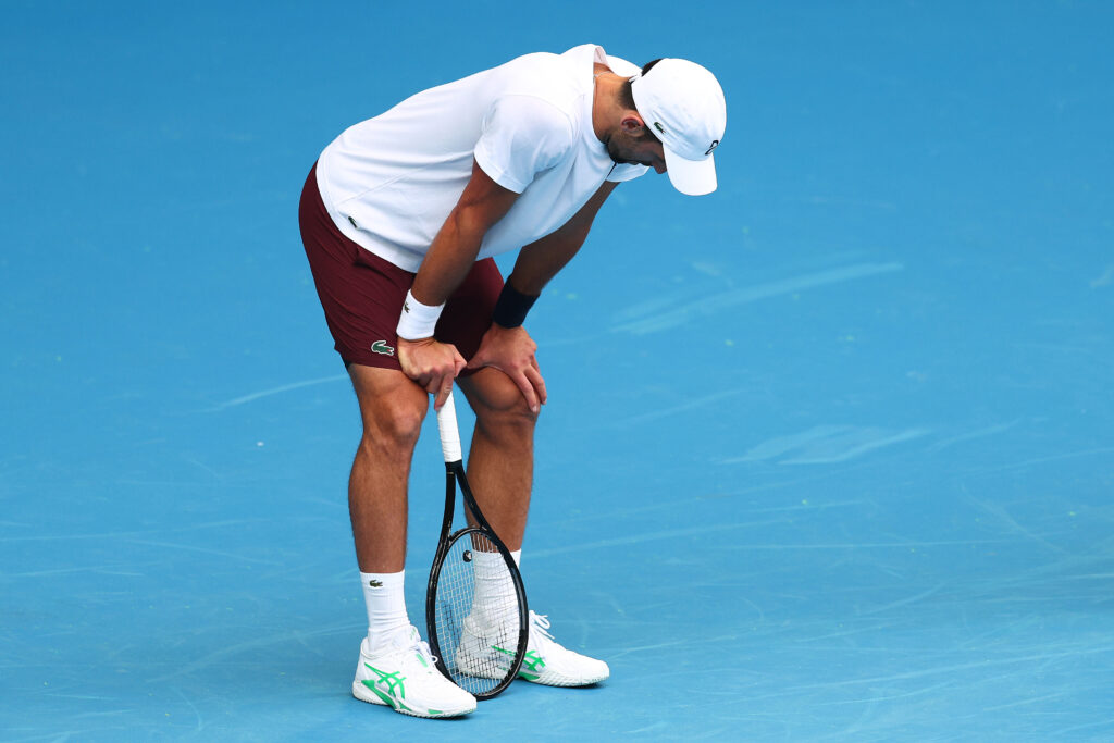Novak Djokovic bent over with his hands on his knees