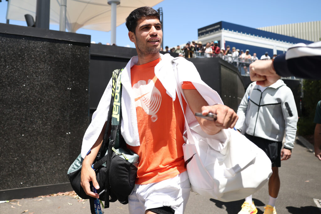Carlos Alcaraz of Spain fist bumps with a fan on his way to a practice court during day five of the 2026 Australian Open at Melbourne Park on January 22, 2026 in Melbourne, Australia.