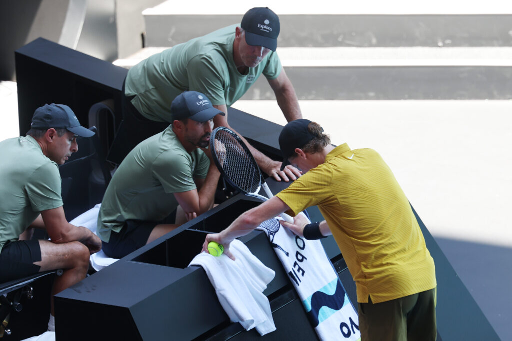 Jannik Sinner of Italy stretches his leg while talking with his team members in the Men's Singles Third Round against Eliot Spizzirri of the United States during day seven of the 2026 Australian Open at Melbourne Park on January 24, 2026 in Melbourne, Australia.