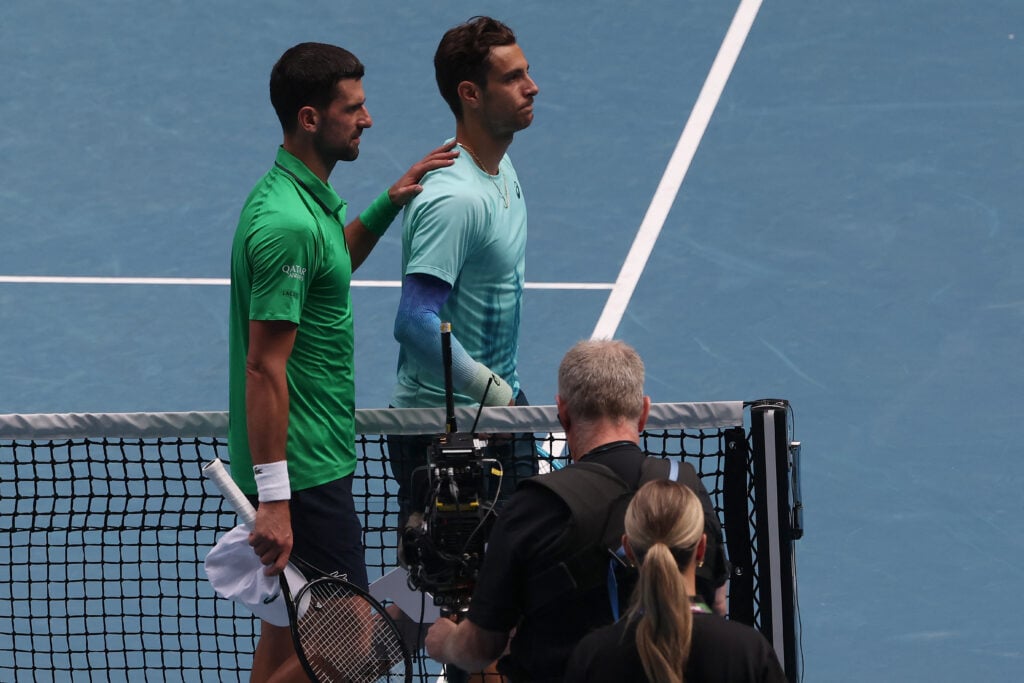 Serbia's Novak Djokovic (L) comforts Italy's Lorenzo Musetti after Musetti retired injured during their men's singles quarter-final match on day eleven of the Australian Open tennis tournament in Melbourne on January 28, 2026.