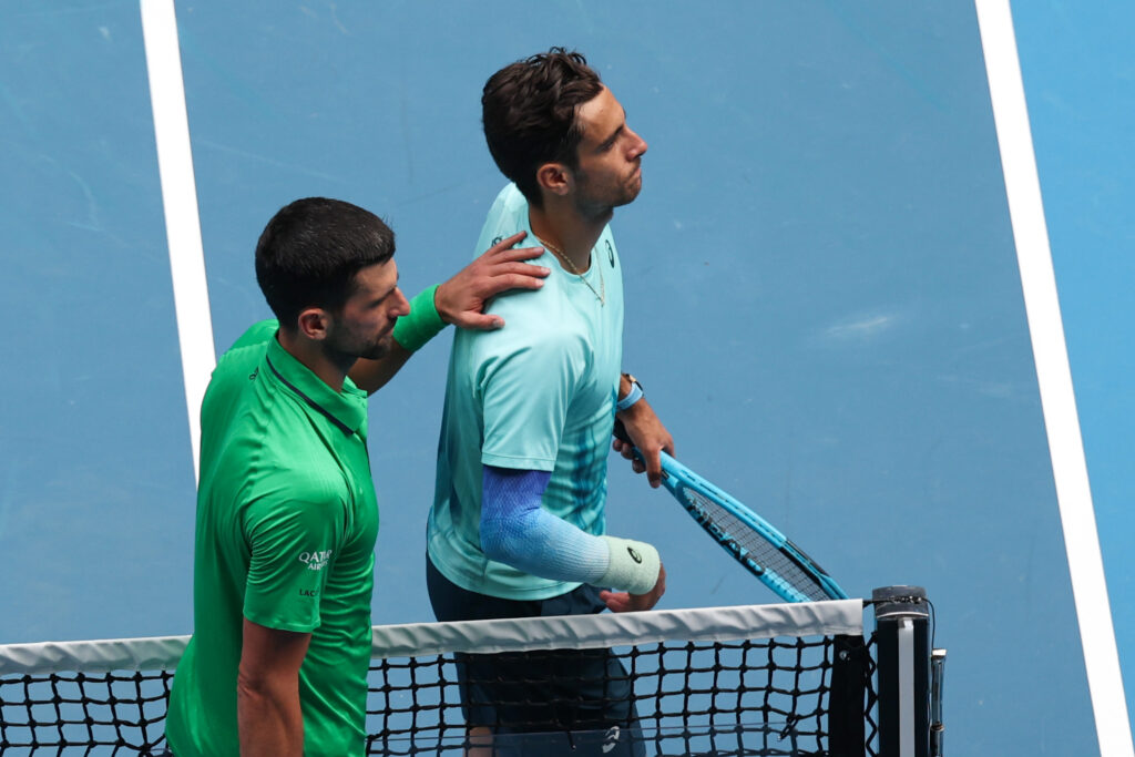 Novak Djokovic of Serbia and Lorenzo Musetti of Italy embrace at the net after their Men's Singles Quarterfinal match during day 11 of the 2026 Australian Open at Melbourne Park on January 28, 2026 in Melbourne, Australia.