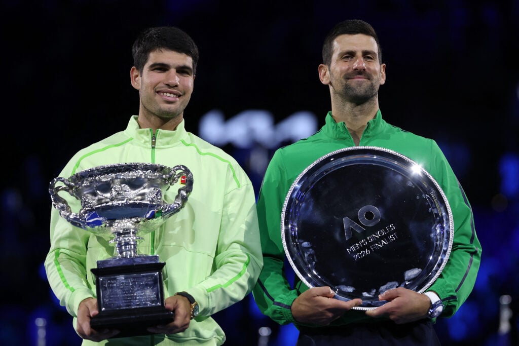 Spain's Carlos Alcaraz (L) and runner-up Serbia's Novak Djokovic pose for photos on the podium after the men's singles final on Day 15 of the Australian Open tennis tournament in Melbourne on February 1, 2026.