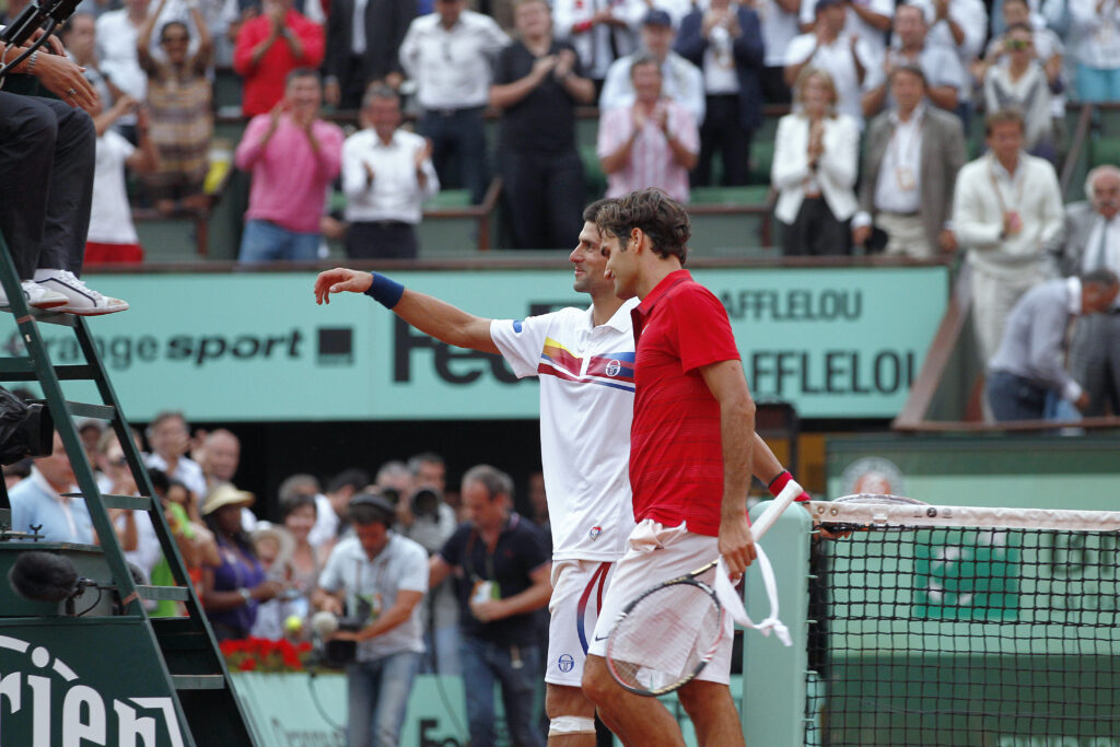 Switzerland's Roger Federer (R) and Serbia's Novak Djokovic shake hands with the Umpire after their semi final match at the French Open tennis championship at the Roland Garros stadium