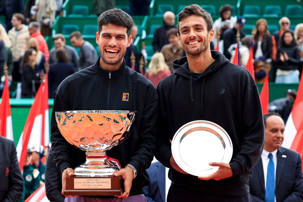 Spain's Carlos Alcaraz (L) celebrates with the trophy after winning against Italy's Lorenzo Musetti the Monte Carlo ATP Masters Series Tournament final tennis match at the Monte Carlo Country Club in Roquebrune-Cap-Martin on April 13, 2025.