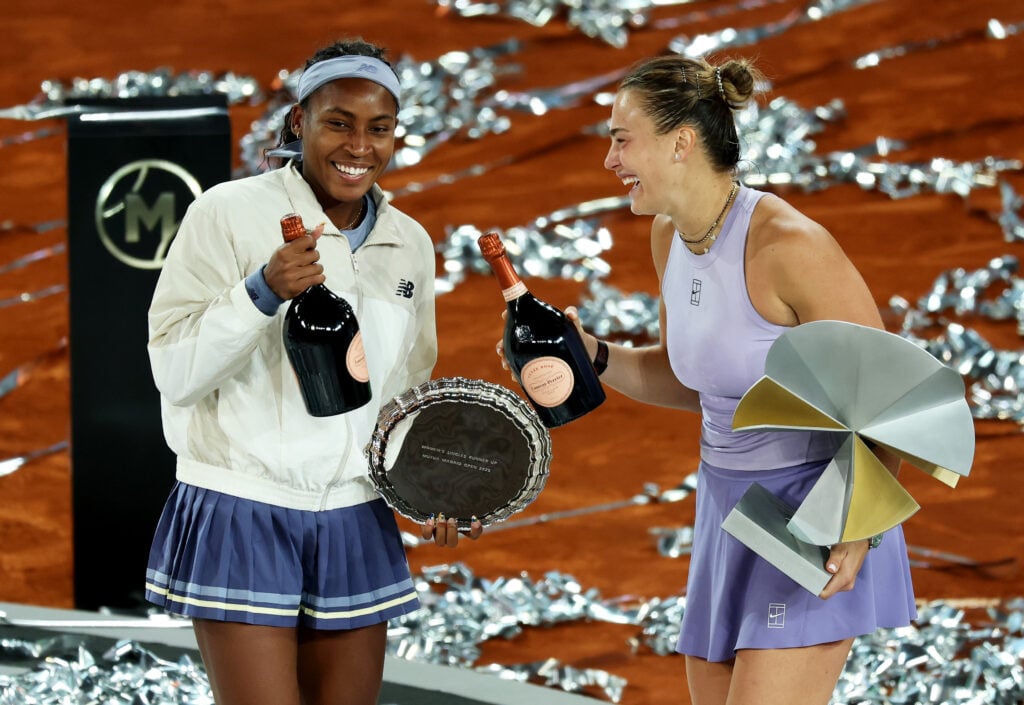 Aryna Sabalenka and Coco Gauff of United States share a joke as they pose for a photograph with bottles of champagne and their trophies after the Women's Singles Final Match on Day 12 of the Mutua Madrid Open at La Caja Magica on May 03, 2025 in Madrid, Spain.