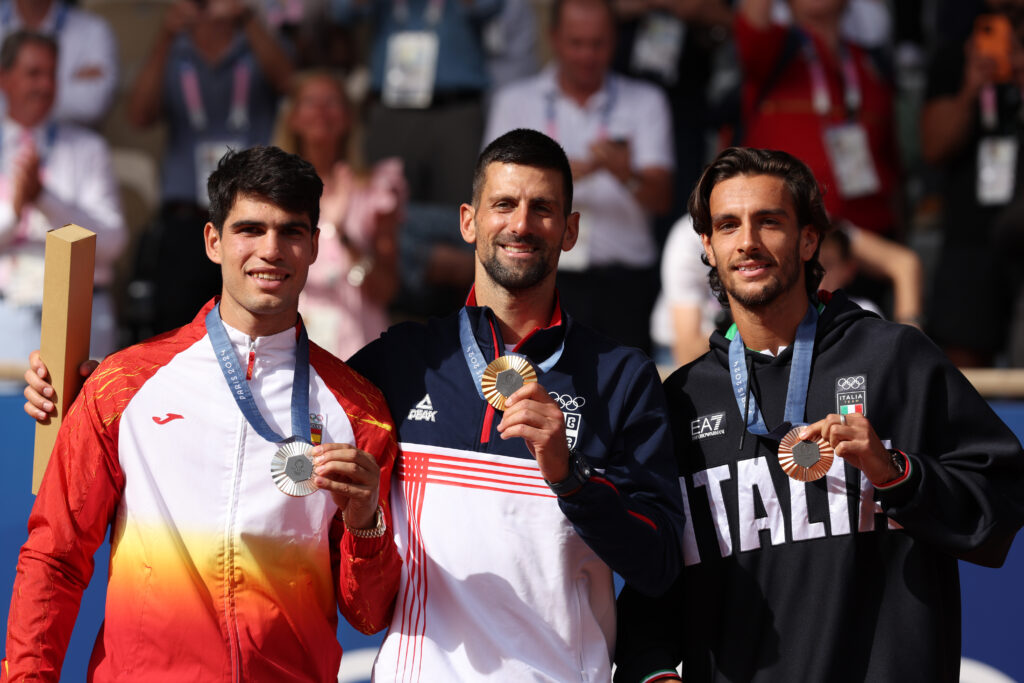 Gold medallist Novak Djokovic of Team Serbia (C), Silver Medallist Carlos Alcaraz of Team Spain (L), and Bronze Medallist Lorenzo Musetti of Team Italy (R) pose on the podium during the Tennis Men's Singles medal ceremony after the Tennis Men's Singles Gold medal match on day nine of the Olympic Games Paris 2024 at Roland Garros on August 04, 2024 in Paris, France.