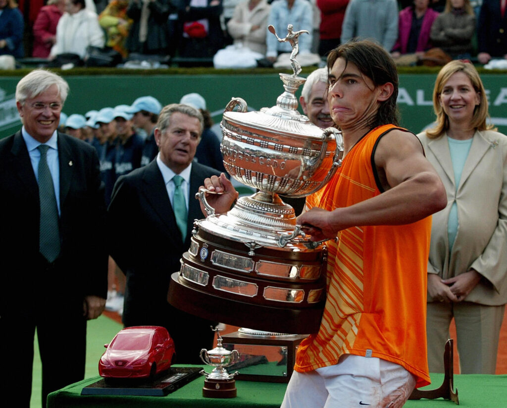 Spanish Rafael Nadal raises the trophy after his victory in the ATP tennis tournament at the Real Club Tenis Barcelona, 24 April 2005 in Barcelona as (L to R:) Joan Clos Mayor of Barcelona, Javier GodoCount of Godo, and Princess Cristina de Borbon watch. Nadal won the final match against Rafael Ferrer 6-1, 7-6, 6-3.