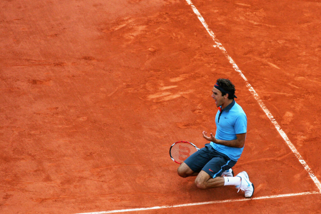 Roger Federer of Switzerland falls to his knees as he celebrates victory during the Men's Singles Final match against Robin Soderling of Sweden on day fifteen of the French Open at Roland Garros on June 7, 2009 in Paris, France.