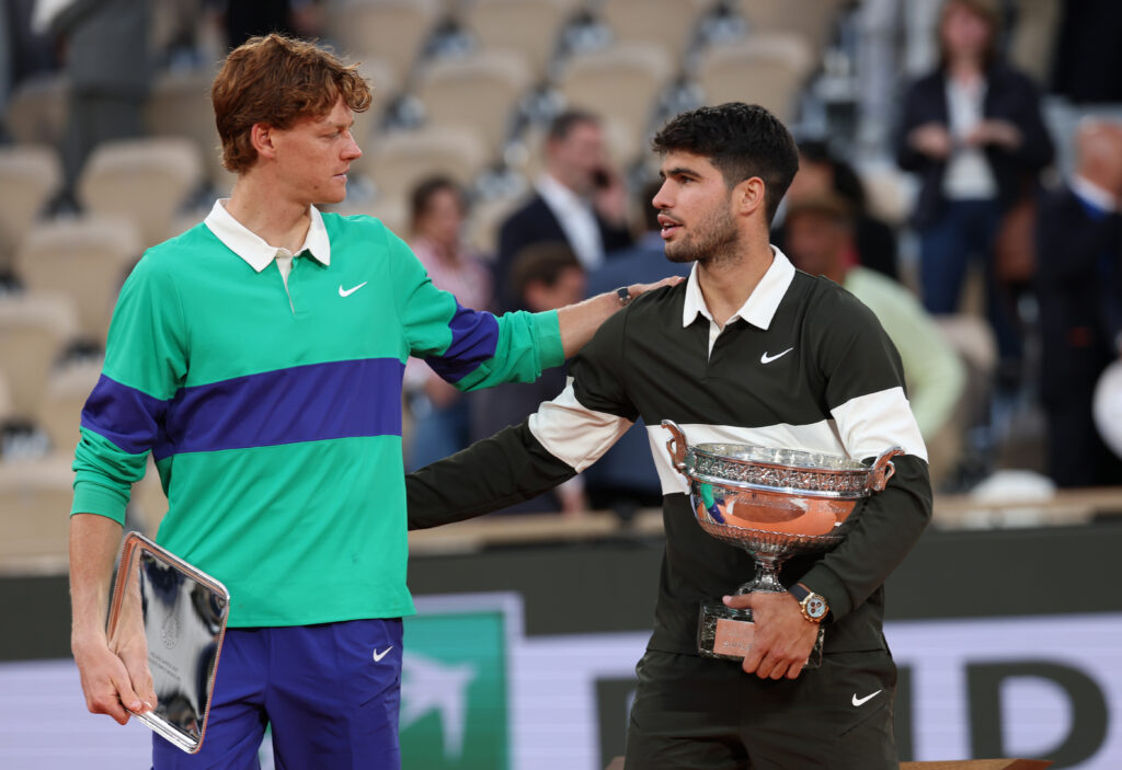 Carlos Alcaraz of Spain holds the Coupe des Mousquetaires trophy as he speaks with runner-up Jannik Sinner of Italy following his victory in the Men’s Singles Final match on Day Fifteen of the 2025 French Open at Roland Garros on June 08, 2025 in Paris, France.