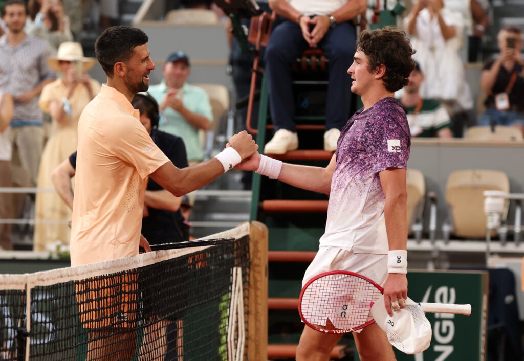 Joao Fonseca shakes Novak Djokovic's hand after beating him at Roland Garros in 2026.