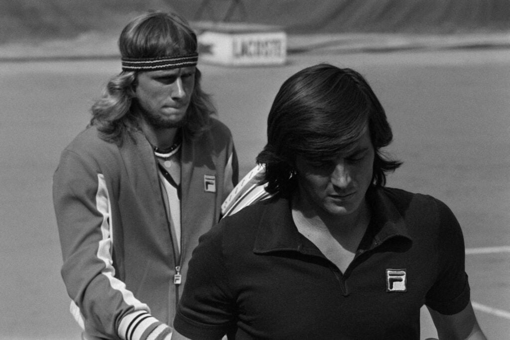 Adriano Panatta walk onto the court for their quarter-final match at the 1976 French Open.