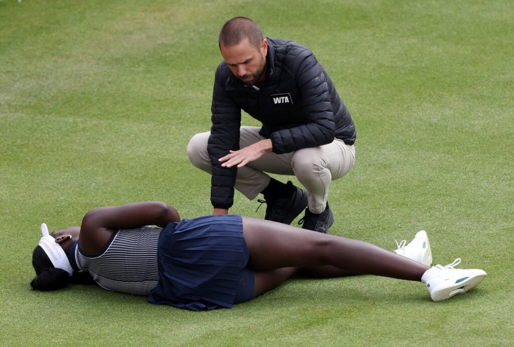 Victoria Mboko is seen to by the umpire after suffering injury at Queen's.