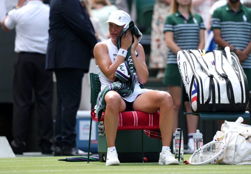 Iga Swiatek, crying, wipes her face with her towel at Wimbledon in 2026.