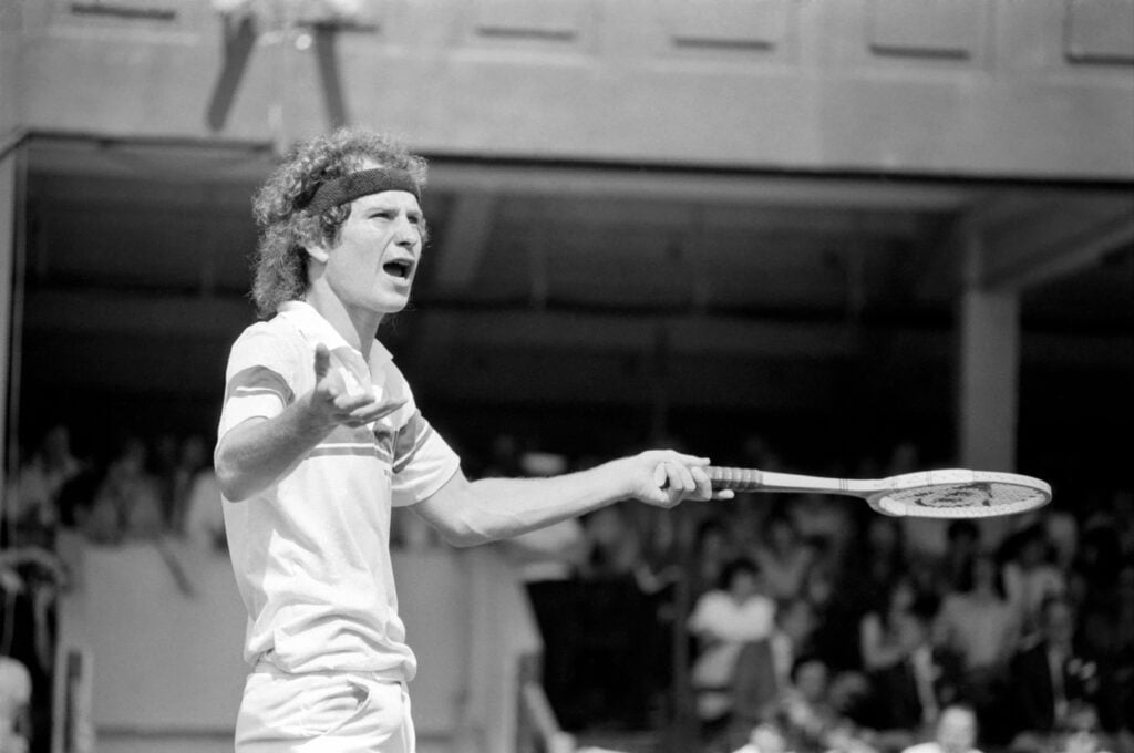 John McEnroe v Tom Gullikson, first round match at Wimbledon on Court Number One, Monday 22nd June 1981. John McEnroe was two flashpoints away from being thrown out of Wimbledon. The number two seed, received one public waring and was then docked 2 penalty points as he beat Tom Gullikson 7-6, 7-5. 6-3 in a bad tempered confrontation on Court One. McEnroe's warning came after he angrily smashed a racket, stamping on the strings and yanking off the handle. Then he was fined the two penalty points for calling umpire Edward James "the pits of the world", and "an incompetent fool".