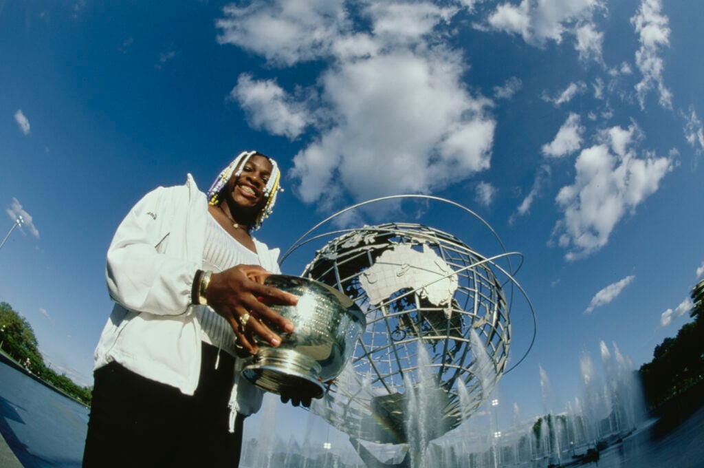 Serena Williams from the United States holds the Mixed Doubles Champion trophy in front of the Unisphere after winning the Mixed Doubles Final match with doubles playing partner Max Mirnyi at the 1998 United States Open Tennis Championship on 11th September 1998 at Corona Park in Flushing Meadow, New York, United States.