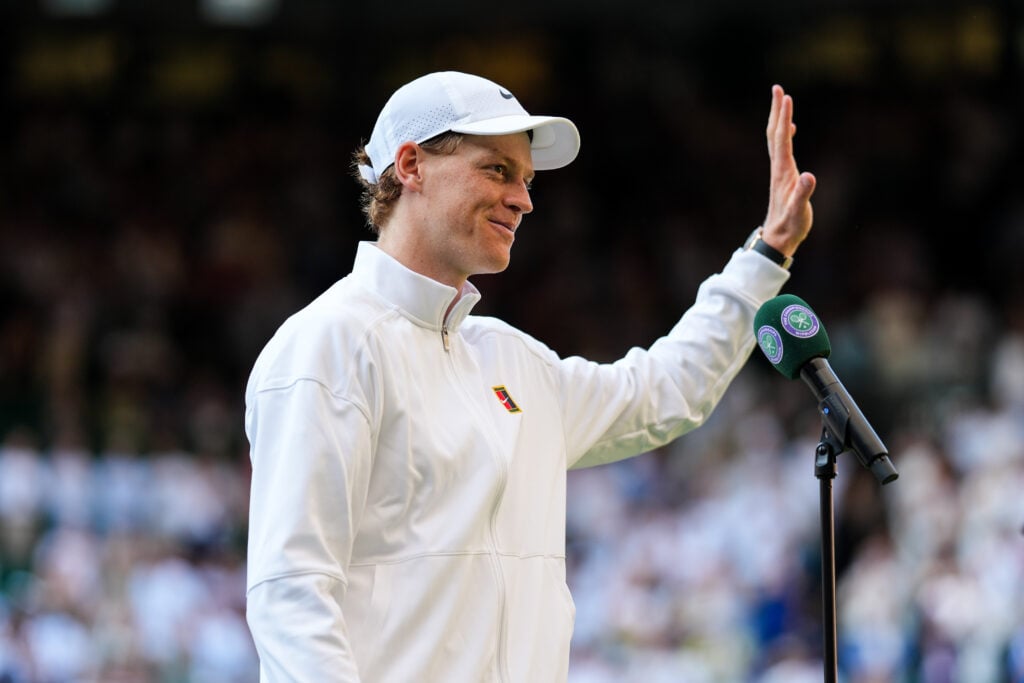 Jannik Sinner waves to the Wimbledon crowd in 2025.