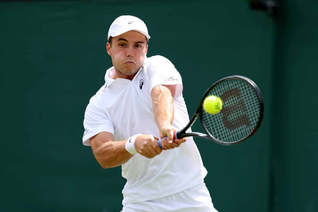 Arthur Fery of Great Britain plays a backhand against Damir Dzumhur of Bosnia and Herzegovina during their Gentlemen's Singles first round match on day two of The Championships Wimbledon 2026 at All England Lawn Tennis and Croquet Club on June 30, 2026 in London, England.