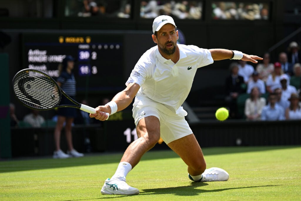 Novak Djokovic of Serbia slides to play a forehand against Arthur Rinderknech of France during their Gentlemen's Singles third round match on day five of The Championships Wimbledon 2026 at All England Lawn Tennis and Croquet Club on July 03, 2026 in London, England.