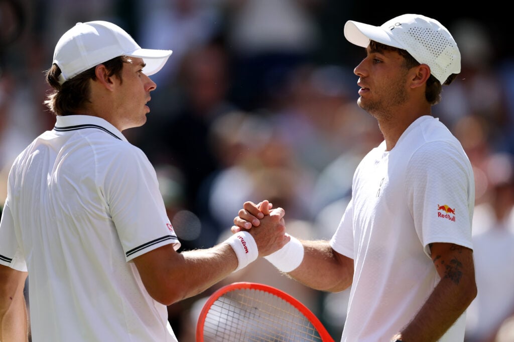 Flavio Cobolli shakes Alex de Minaur's hand after beating him at Wimbledon in 2026.